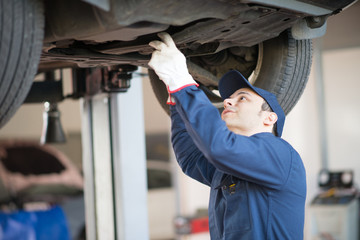 Obraz na płótnie Canvas Mechanic repairing a lifted car