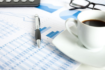 Coffe, eyeglasses and a calculator over documents