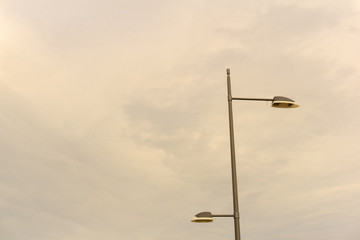 Two lamps below a cloudy sky