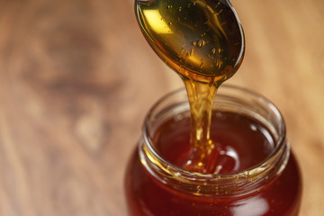 organic honey drips from spoon in jar