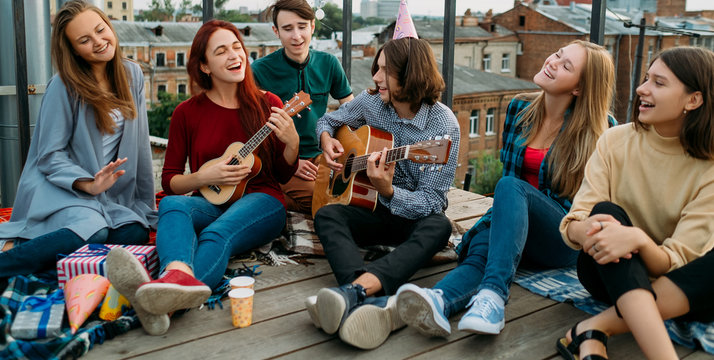 Group of friends hangout. Singing to a guitar. Free spirits lifestyle. Urban hipster teenagers leisure