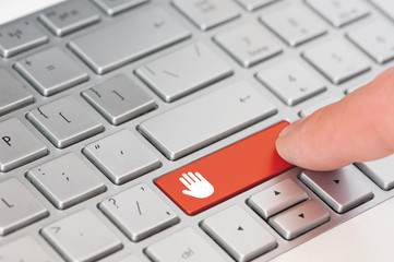 A finger press a red key with stop palm icon symbol on laptop keyboard