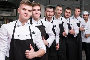 Contestants of a tv cooking talent show stand in a row ready to show their skills in the...