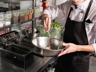 Student cook working at his summer or side job preparing food at a restaurant. Chef skills training