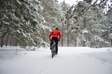 Cyclist in Red Riding Mountain Bike in Beautiful Winter Forest. Extreme Sport and Enduro Biking Concept.