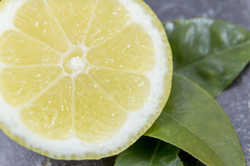 Sliced lemon with leaves on grey background