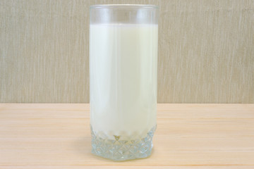 Glass of milk standing on wooden table