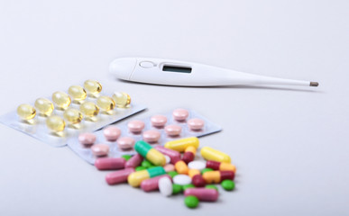 Pills and medical thermometer on white background. .