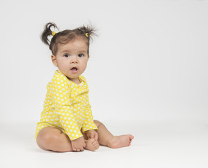 Cute, baby girl in yellow onesie, sitting on white background - 189975963