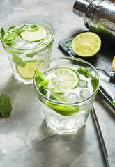 Mojito cocktail with lime and mint in highball glass on a stone table. Drink making tools and ingredients for cocktail