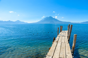 Wooden pier at Lake Atitlan on the beach in Panajachel, Guatemala. With beautiful landscape scenery of volcanoes Toliman, Atitlan and San Pedro in the background. Volcano Highland in Central America.