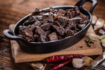 braised beef and lamb meat, liver, lungs and heart dish in black iron cast heavy dish