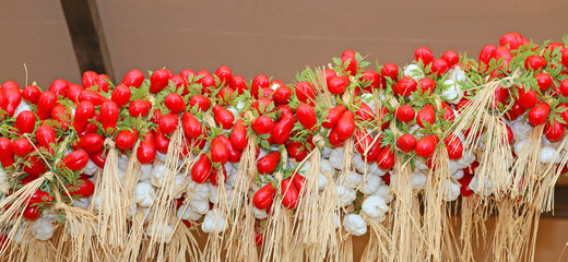 red tomatoes and garlic hanging for sale