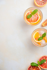 Cold refreshing drink with blood orange slices in a glass on a white concrete background. Top view,...