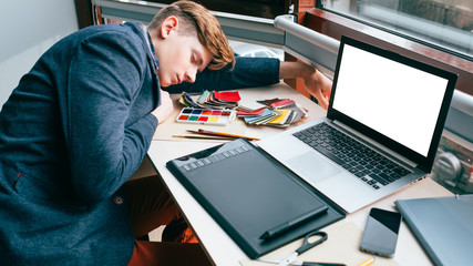 Overworking fatigue. Exhausted tired designer sleeping on the desk in his workplace. Inefficient work planning. Graphic tablet, laptop with white screen - Powered by Adobe
