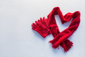 red gloves and scarf as heart on snow