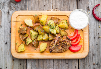 Roasted whole chicken with potatoes and thyme in a cast iron skillet