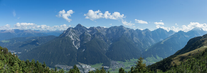 Panorama of an Austrian village in a valley. A few clouds in the sky on a sun filled day over an isolated town in the alps.