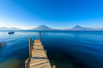 Wooden pier at Lake Atitlan on the beach in Panajachel, Guatemala. With beautiful landscape scenery of volcanoes Toliman, Atitlan and San Pedro in the background. Volcano Highland in Central America.