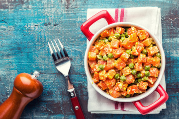 Carrot braised with fresh green peas in creamy milk sauce in stewpan, stewed vegetable saute, top view