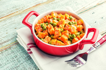 Carrot braised with fresh green peas in creamy milk sauce in stewpan, stewed vegetable saute