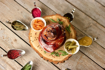 Pork knuckle with many different side dishes. Pork knuckle on wooden plate with many differend side dishes around, down view.