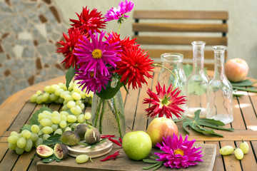 Still life with dahlias and apples, grape, figs  and antique bottles