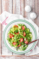 Healthy vegetable salad of fresh tomato, cucumber, spinach, frize and arugula on plate. vegan dish. top view