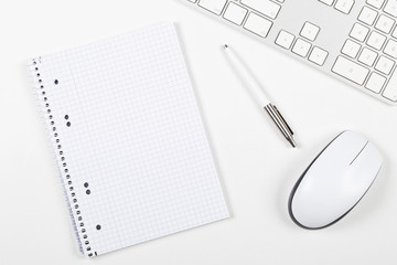 White office desk top view with computer mouse, keyboard, notepad and pen