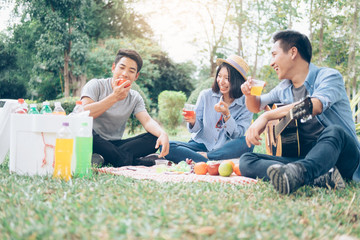 Young teen groups having fun picnic in park together.