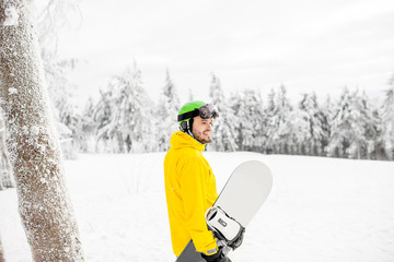 Fototapeta na wymiar Man in winter sports clothes walking with snowboard at the snowy mountains