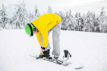 Man in winter sports clothing wearing a snowboard outdoors on the snowy mountains