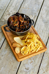 Top view saucepan with mussels and side dish. Dish with mussels on wooden board, top down view.