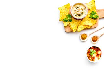 Middle Eastern cuisine. Bowl with hummus among pieces of crispbread and spices on white background top view copy space