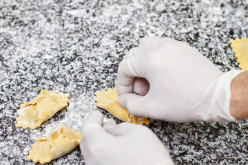 Hands cooking ravioli pasta close up. Making ravioli on kitchen table.