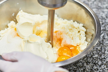 Start stirring cream in bowl with motor mixer, baking cake. Mixing flour, sugar and eggs by hand to make a thick dough. First step of mixing.
