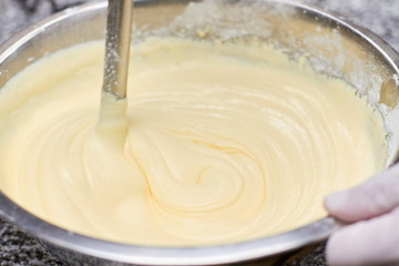 Stirring batter in bowl, close up. Metal mixer mixing around batter.