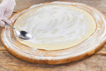Pizza basis white sauce smearing. White sauce spreading on dough pizza basis.