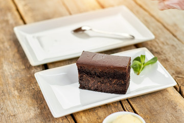 Rectangle Piece of Belgian chocolate cake. Piece of black cake on white plate. Rectangle plate with dessert.