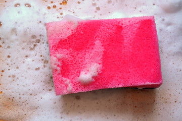 Pink sponge with white soap foam on wooden table