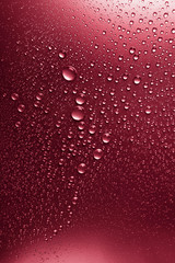 Bubbles of water on a shaded surface, red background