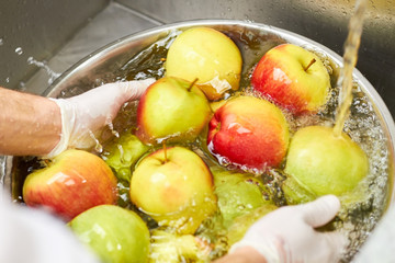 Apples sinking and washing by chef. Pile of apples in a water in a sink.