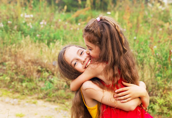 Two Cute little girls embracing and laughing at the countryside. Happy kids outdoors