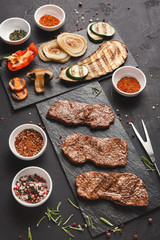 Small pork steaks on black background