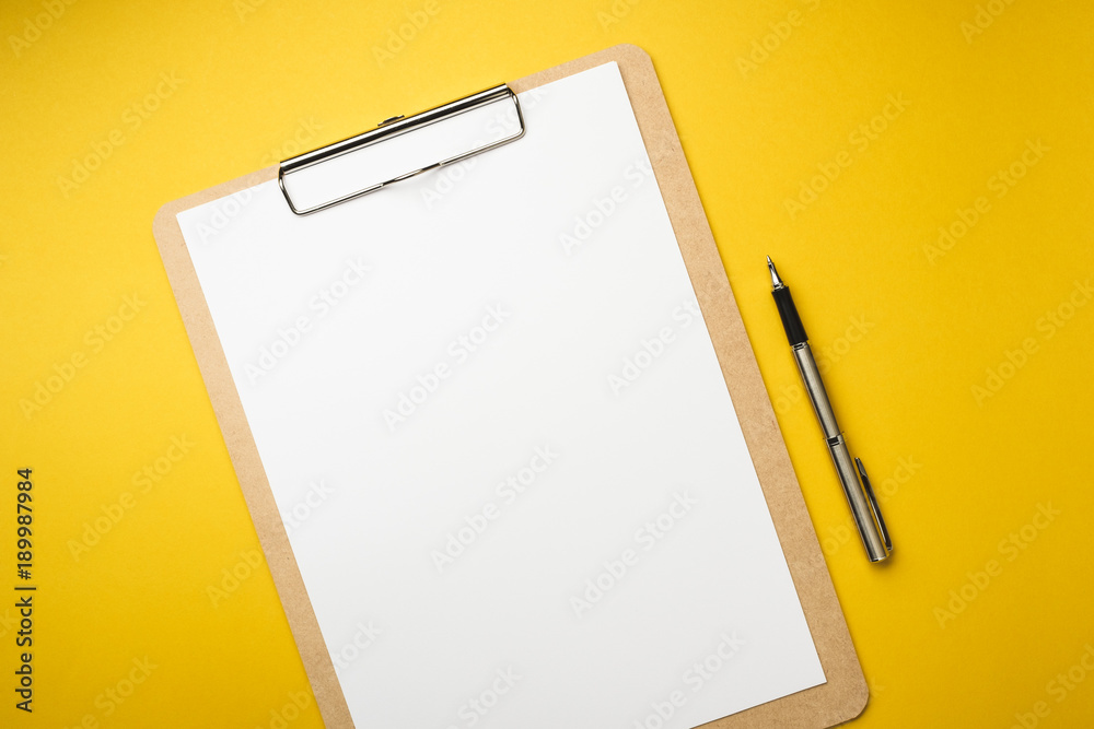 Wall mural wood clipboard with empty white paper and pen isolated on yellow background - Wall murals