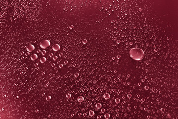 Bubbles of water on a shaded surface, red background