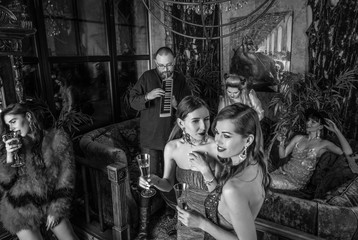 Group of young stylish people dressed classical style in interior of luxury club. Black-white photo.