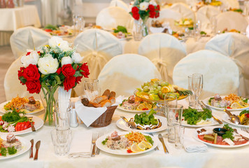 Beautifully set festive table, decorated with a bouquet of roses. The preparations for the party.