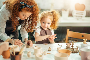 redhad Mother and two kid daughter at home molded from clay and play together