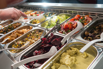 Mann bei Selbstbedienung an Salatbüffet in Kantine zum Mittagessen